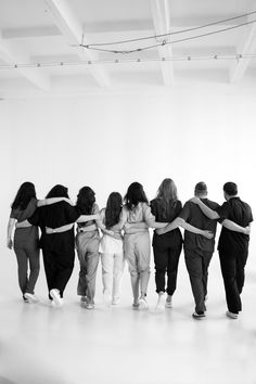 a group of people standing in a room with their arms wrapped around each other's backs