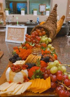 an assortment of cheeses and fruits on a wooden platter with a turkey shaped basket in the background