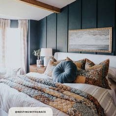 a bedroom with blue walls and white bedding is pictured in this image, there is a painting on the wall above the bed