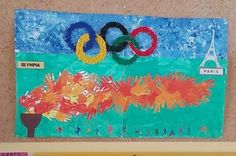 the olympic symbol is displayed on a bulletin board in front of an art work by students