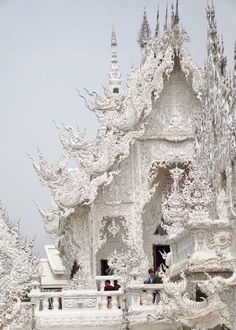 people are standing in front of a white building with snow on the roof and windows