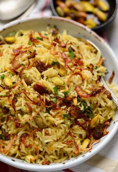 a white bowl filled with lots of food on top of a checkered table cloth