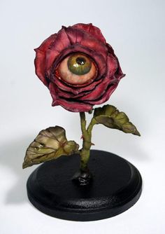 an eyeball is placed on top of a rose with two leaves in front of it