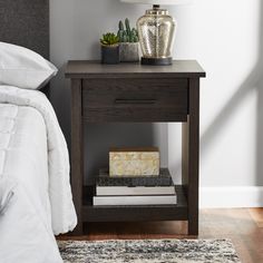 a nightstand with books on it next to a bed