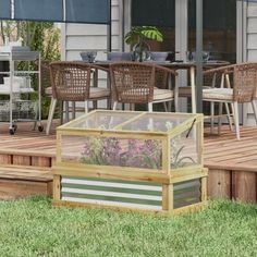 a glass box sitting on top of a wooden deck next to a table and chairs