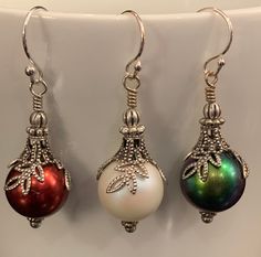 "Add a festive feel to your holiday wardrobe. Featuring 12mm Swarovski pearls with silver floral bead caps, filigree bell caps and antique silver findings that create the look of beautiful ornaments. Sterling silver ear wires and findings complete these fun to wear holiday earrings. Earring length: 1.5\" (including ear wire) All Moon Grove Designs jewelry comes beautifully gift boxed and ready for giving to yourself or someone special." Elegant Nickel-free Jewelry For Holiday, Elegant Beaded Earrings For Holiday, Silver Earrings With Bead Caps And Round Beads, Silver Earrings With Round Beads And Bead Caps, Elegant Silver Earrings With Bead Caps, Silver Earrings With Round Beads For Celebration, Silver Jewelry With Round Beads For Holidays, Ornament Earrings, Pearl Ornaments