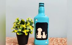 a blue bottle with a dog on it next to a potted plant and a flower