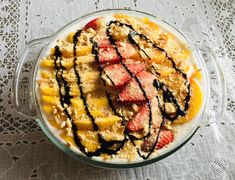 a dessert dish with strawberries and other toppings in a glass bowl on a lace tablecloth