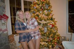 two women standing in front of a christmas tree