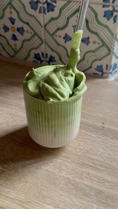 a cup filled with green whipped cream on top of a wooden table