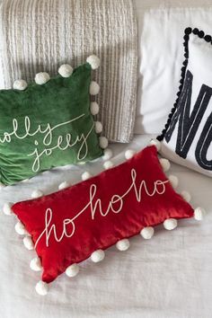 three pillows on a bed with pom - poms and one pillow that says merry hoho