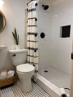 a white toilet sitting in a bathroom next to a walk in shower with black and white tile