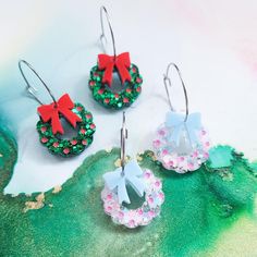 three pairs of earrings with bows on them sitting on top of a green surface,