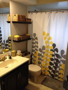 a bathroom with yellow and gray decor on the shower curtain, toilet and sink area