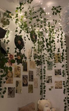 a teddy bear sitting on a couch in front of a wall covered with plants and pictures