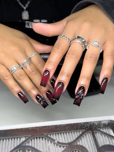 a woman's hand with red and black nail polish on it, holding onto her ring