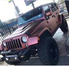 a pink jeep parked in front of a fence