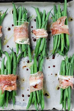 green beans wrapped in bacon and other toppings on a sheet of parchment paper, ready to be cooked