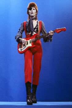 a man in red pants holding a guitar