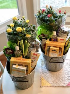 two metal buckets filled with flowers on top of a table next to a window