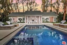 a house with a pool in front of it and lounge chairs around the pool area