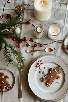 the table is set with ginger cookies and silverware, candles, and greenery