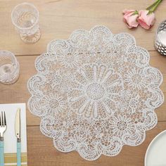 a white doily sitting on top of a wooden table next to plates and utensils