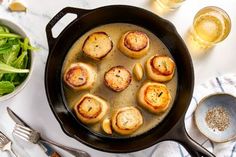 some food is cooking in a skillet on a table with other dishes and utensils