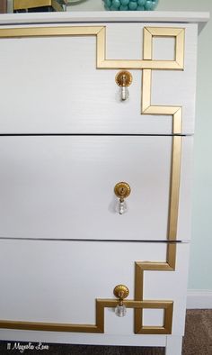 a white dresser with gold trim and handles