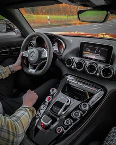 a man driving a car on the road with his hands on the steering wheel and dashboard