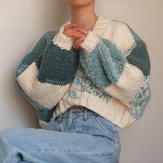 a woman sitting on the floor wearing a sweater and jeans