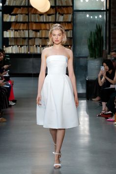 a model walks down the runway in a white dress with high collars and strapless heels