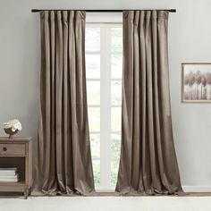 a living room with a large window covered in beige curtains and white carpeted flooring