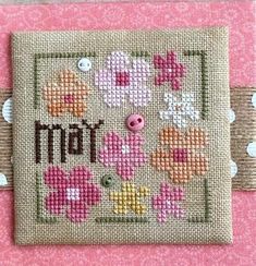 a cross stitch pattern on a pink background with the word mom written in brown letters