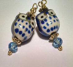 two blue and white glass owls with gold accents on them'earwires, sitting next to each other