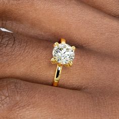 a woman's hand with a yellow gold ring on it and a diamond in the middle