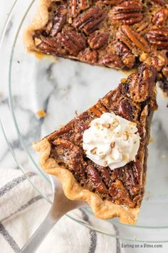 a pecan pie with whipped cream on top is cut into slices and sits on a glass plate