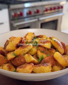 a white bowl filled with fried potatoes on top of a wooden table next to an oven