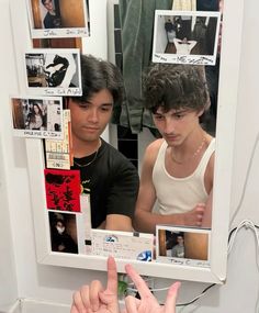 a young man is looking at himself in the mirror and pointing to his own finger