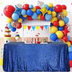 a blue table topped with balloons next to a blue table cloth covered table and wall