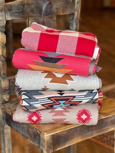 four blankets stacked on top of each other on a wooden chair in front of a wood floor