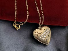 "Description: A classic vintage 14K gold filled heart shaped locket necklace with a raised white gold filled message that someone is special with some etched flower designs on the front that hangs on a new 14K gold filled chain. The heart has the words \"Someone Special\" in a silver color (white gold fill) in a cursive font that appears diagonally across the locket front. Above and below this are some etched accent lines that appear to be leafy. All around the heart is a zig zag etched border t Retro Era, Cursive Font, Photo Necklace, Someone Special, Heart Locket, 2 Photos, Locket Necklace, Classic Vintage, Estate Jewelry