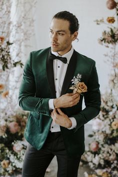 a man in a tuxedo and bow tie holding a boutonniere