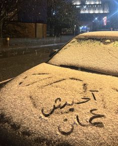 a car covered in snow on a city street at night with the word'i love you'written on it