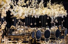 an elaborately decorated dining room with black chairs and white flowers hanging from the ceiling