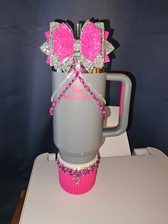 a pink and gray coffee cup with two bows on it's head sitting on a table