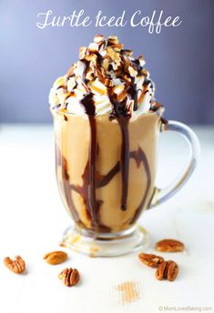 a cup filled with coffee and topped with whipped cream, chocolate sauce and pecans