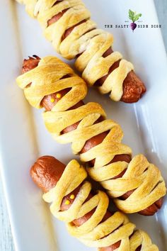 hot dogs wrapped in bread on a white plate