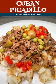 a white plate topped with potatoes and meat covered in olives next to a red sign that says cuban picadillo