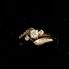 a gold ring with two diamonds on it's sides, sitting on a black surface